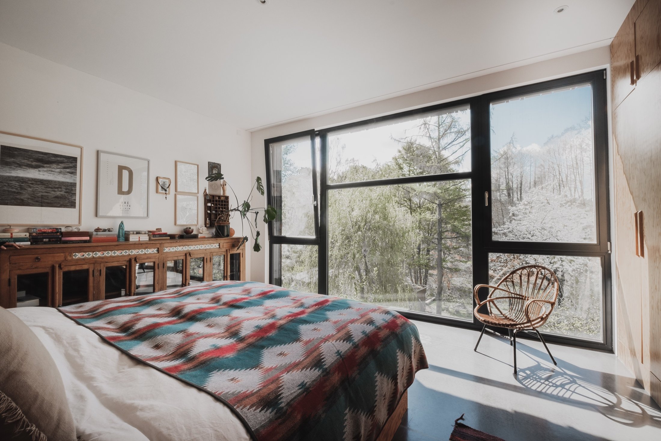 Schlafzimmer mit Kelim-Decke, Rattansessel und Blick in den Wald, Das schwarze Haus