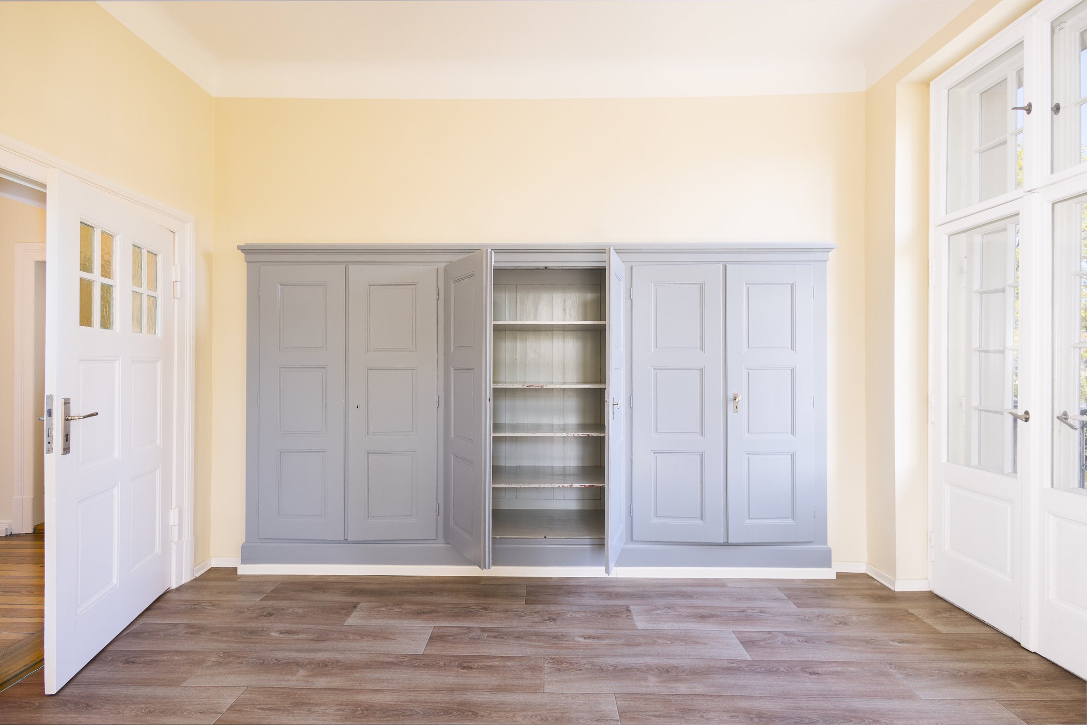 Zimmer mit grauem Einbauschrank, Sprossenfenstern und Vinylboden, Projekt Schütze Immobilien