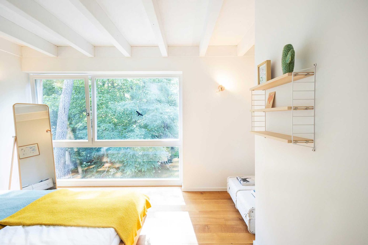 Holzhaus: Schlafzimmer mit Holzbett, gelber Decke und Fenster zum Wald